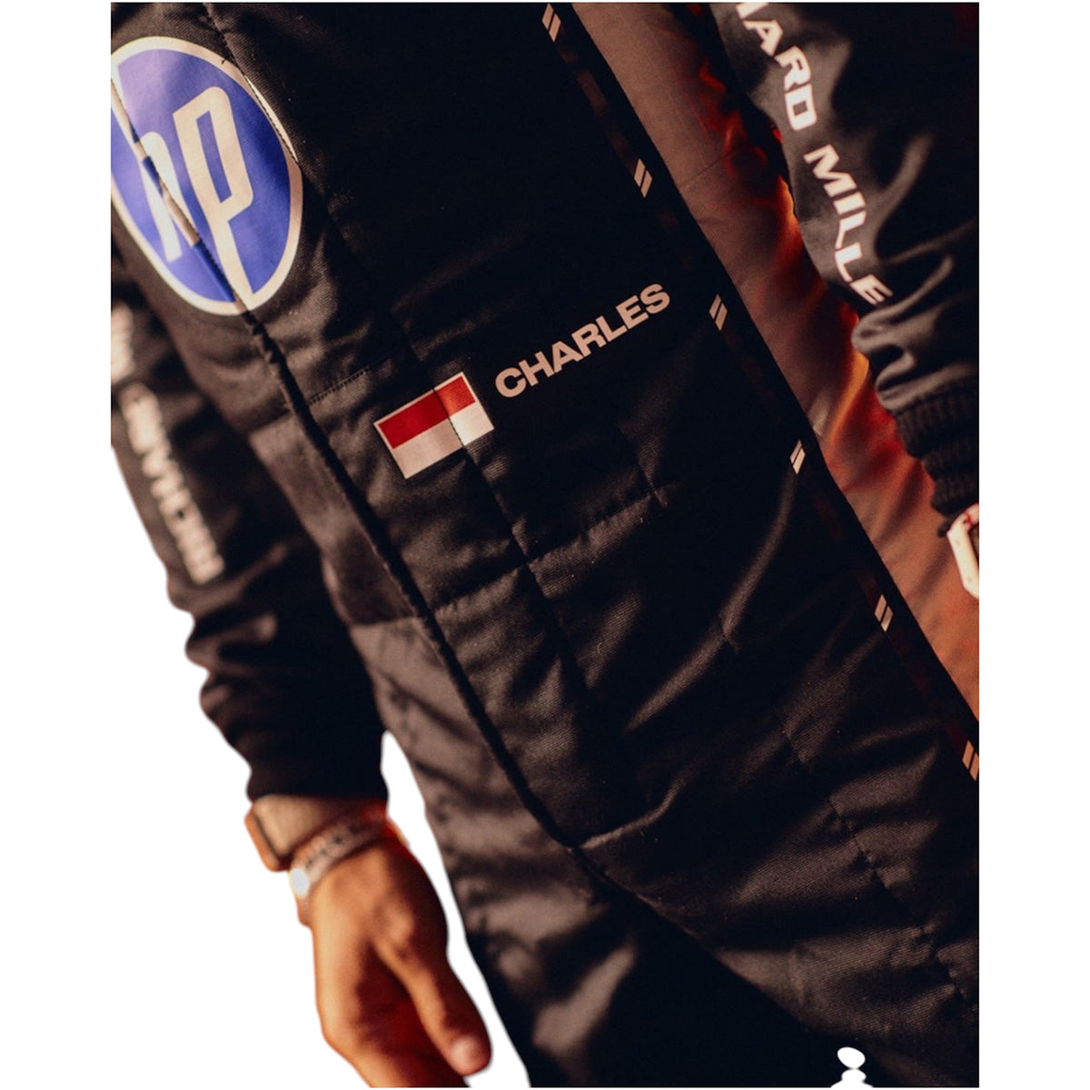 Close-up racing suit with "CHARLES" patch and flag emblem on dark fabric