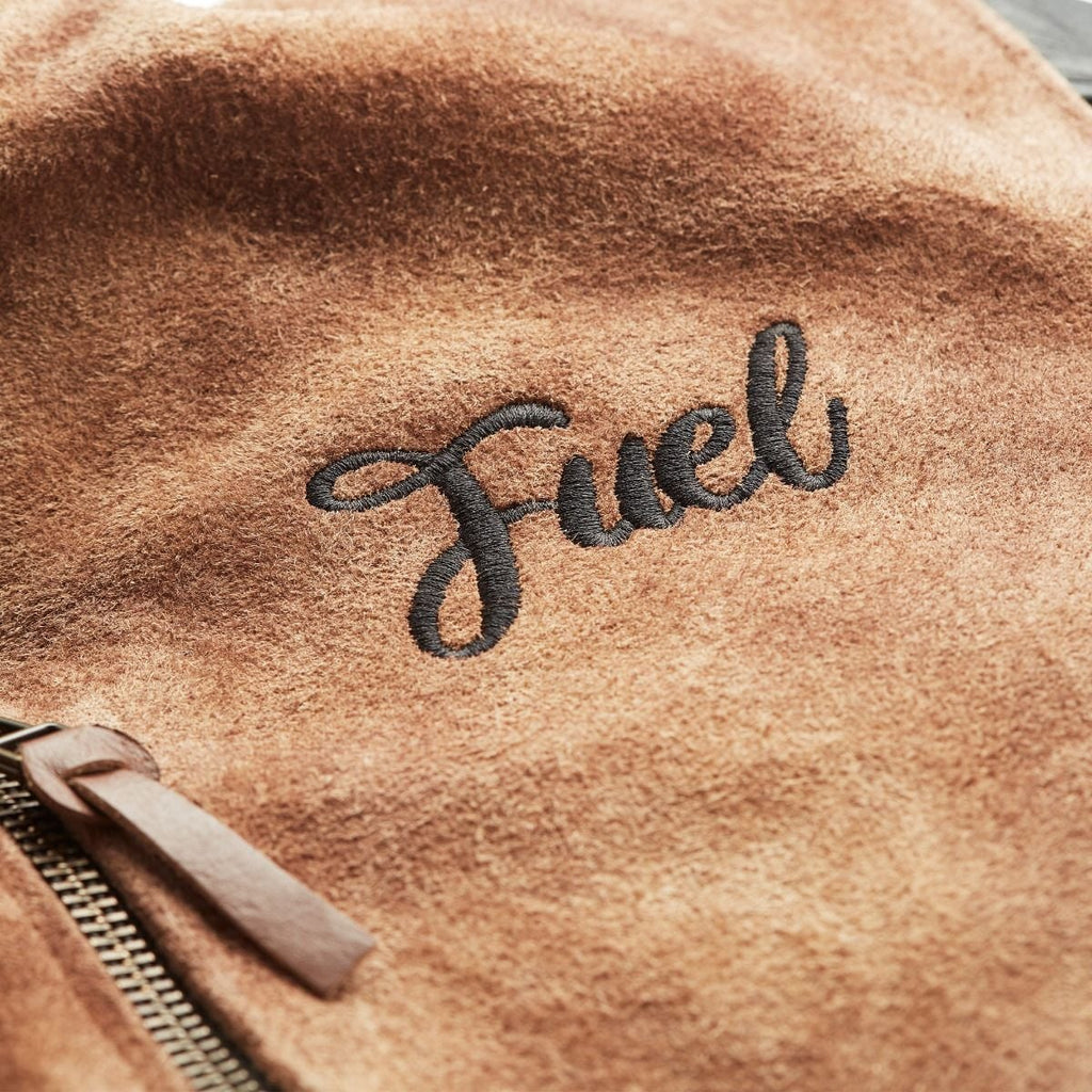 Close-up of black Fuel embroidery on the tan suede jacket