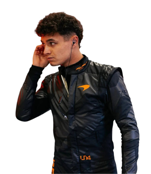 Black racing driver suit close-up, high collar and orange chest marking.
